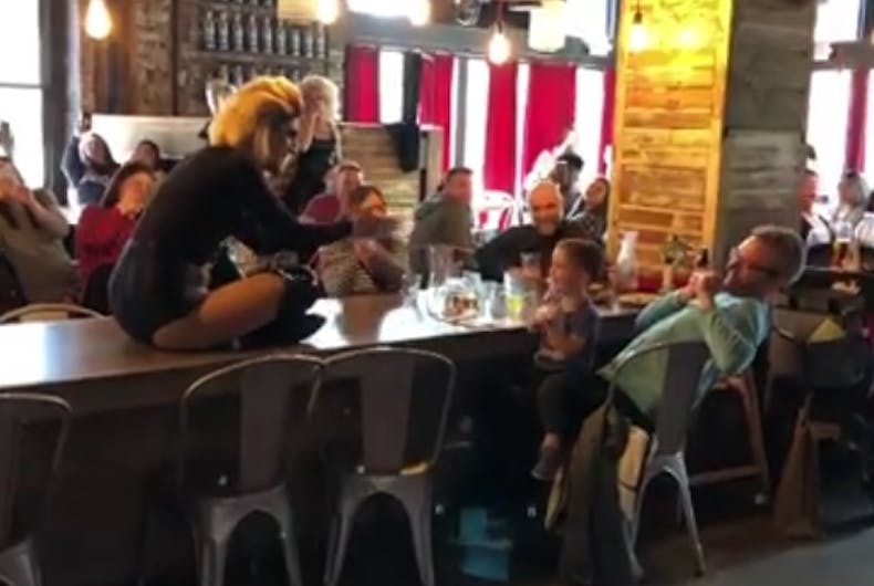 The drag queen on a table performing the song for the baby.
