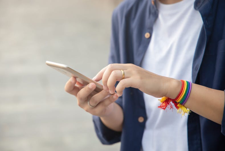 shutterstock_1617433480 modern LGBT woman with ribbon symbol using smartphone