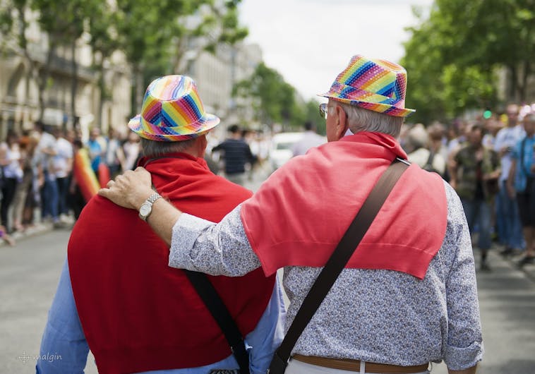 An elderly gay couple in rainbow hats