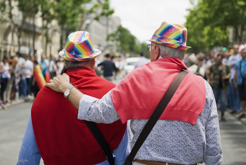 An elderly gay couple in rainbow hats